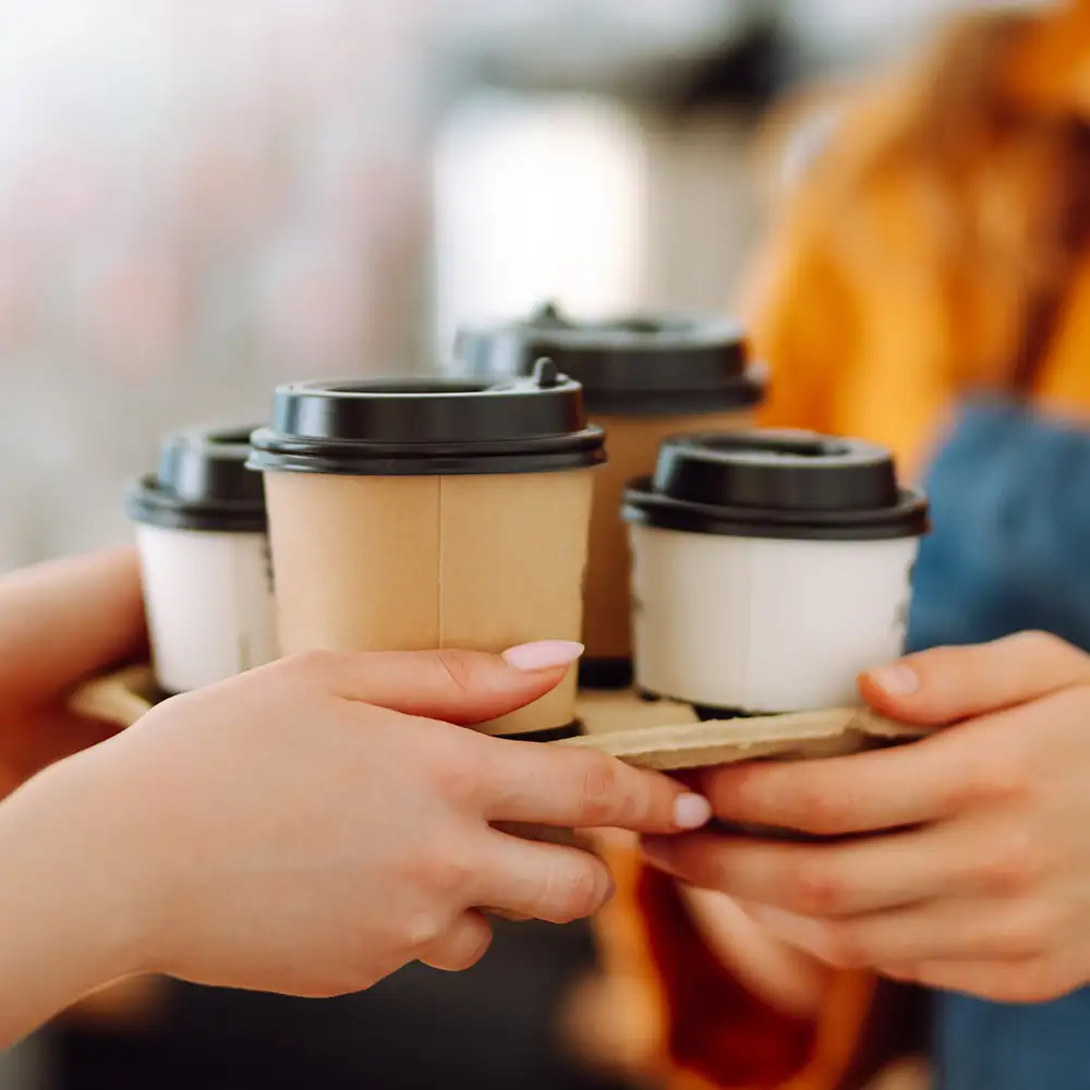 Konzept für Lebensmittel zum Mitnehmen. Eine schöne Barista-Frau gibt einem Kunden Kaffee zum Mitnehmen. Essen und Trinken.